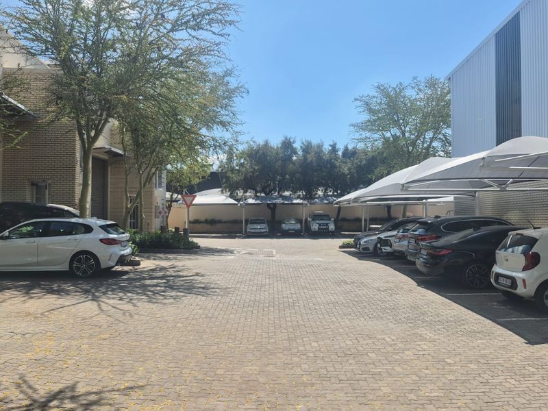 Industrial property exterior featuring a paved parking area with multiple shade cloth carports and brick warehouse structures.