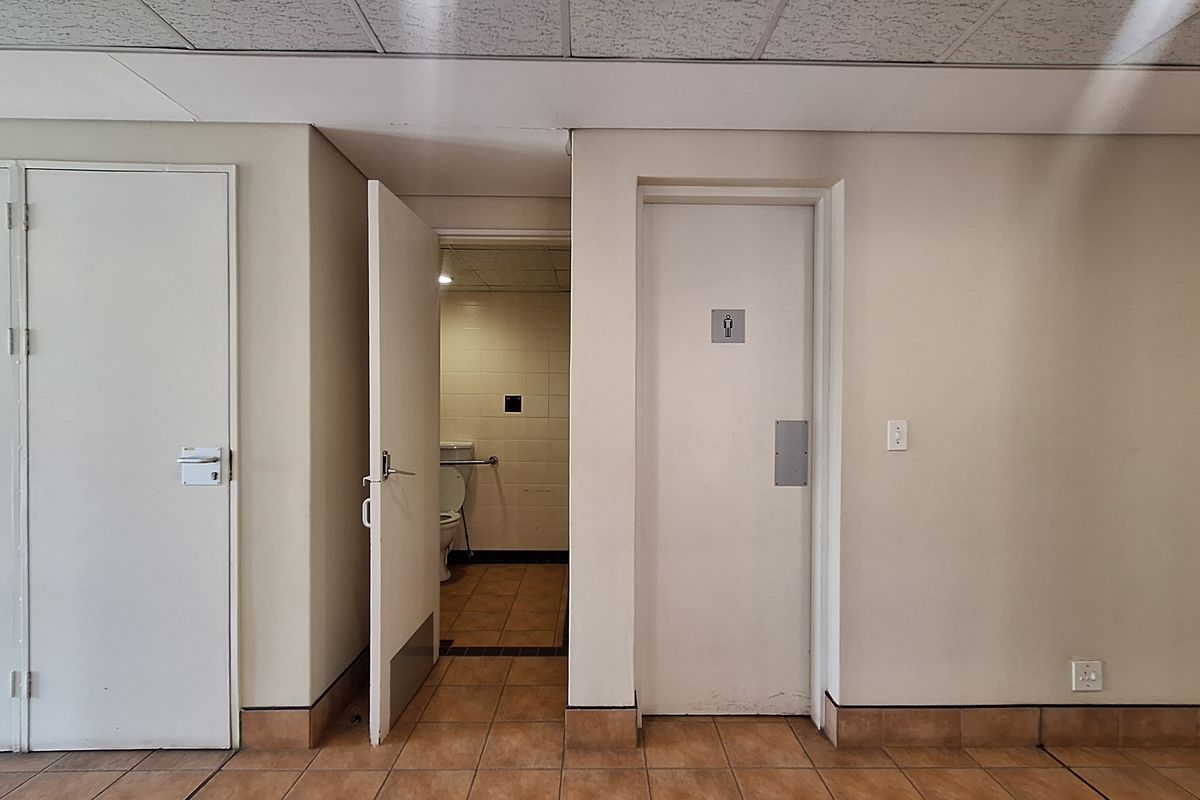 A functional office restroom area featuring tiled flooring, a suspended ceiling, and a designated accessible toilet facility.