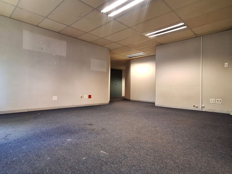 An empty office space featuring a suspended ceiling with recessed lighting, carpeted flooring, and multiple electrical and data points.