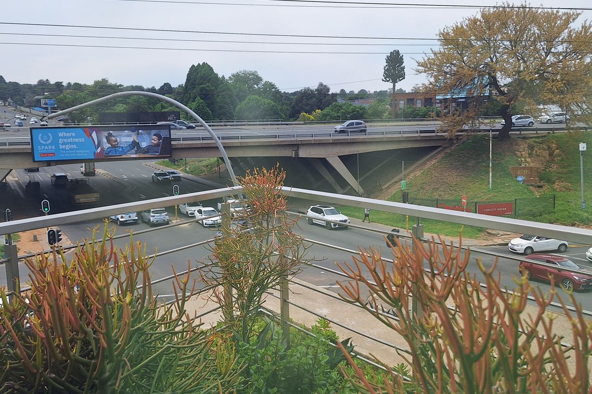 An elevated view overlooking a busy intersection and highway overpass, featuring a modern metal balustrade in the foreground.