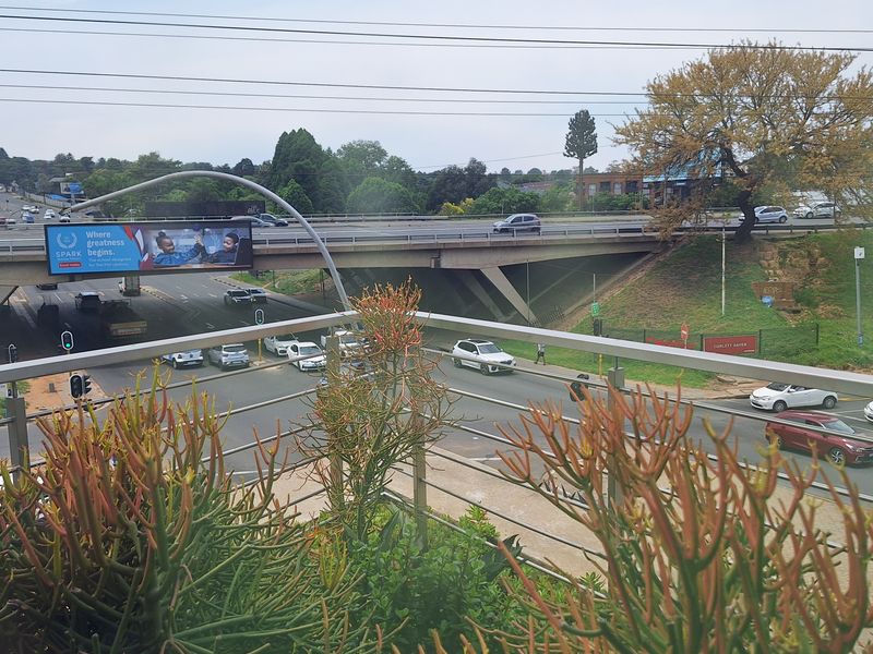 An elevated view overlooking a busy intersection and highway overpass, featuring a modern metal balustrade in the foreground.