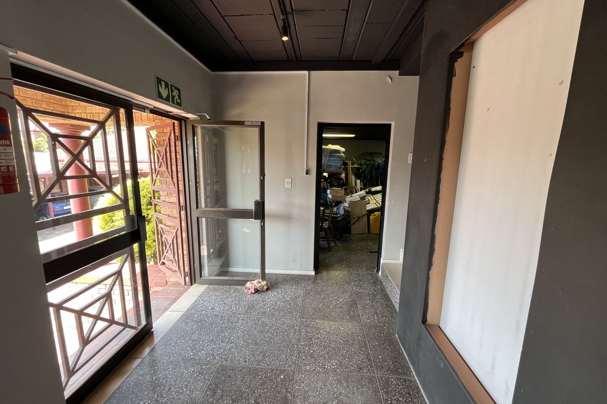Entrance area featuring tiled flooring, exposed ceiling with track lighting, and an aluminium glass door leading to the exterior.