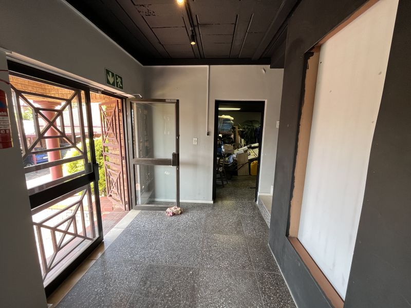 Entrance area featuring tiled flooring, exposed ceiling with track lighting, and an aluminium glass door leading to the exterior.