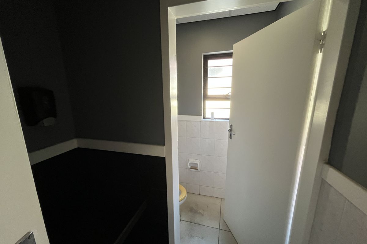 A small bathroom featuring tiled walls and flooring, with a window providing natural light. The space is functional but requires cosmetic updates.