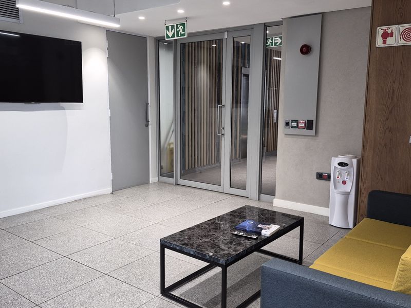 A modern commercial reception or waiting area featuring tiled floors, glass entrance doors, and integrated fire safety infrastructure.