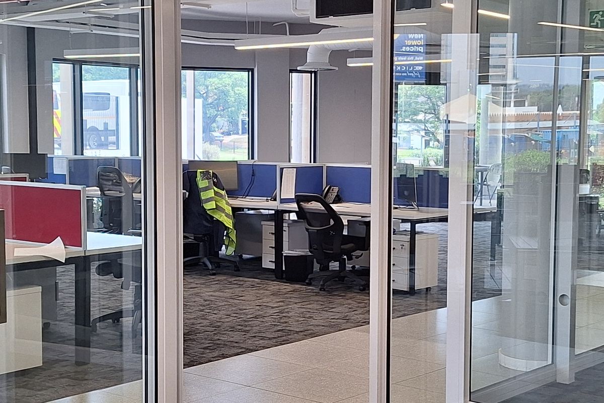 Modern open-plan office space featuring glass partitioning, suspended ceilings with linear lighting, and a mix of carpeted and tiled flooring.