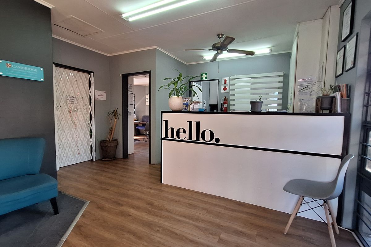 A professional commercial reception area featuring a built-in desk, laminate flooring, and secure access points, providing a welcoming entry for clients.