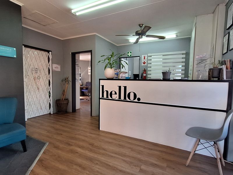 A professional commercial reception area featuring a built-in desk, laminate flooring, and secure access points, providing a welcoming entry for clients.