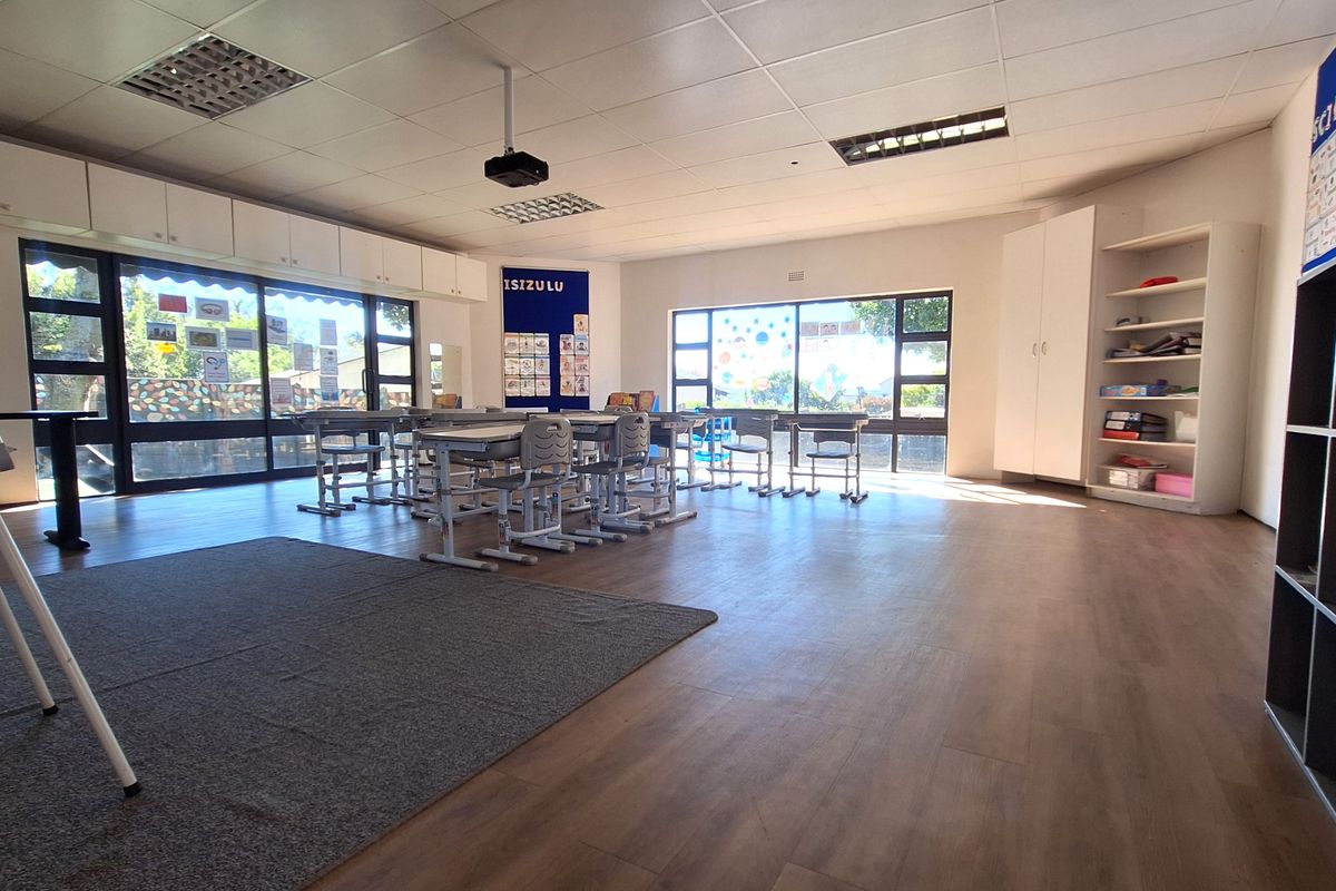 A bright and spacious classroom or office area featuring laminate flooring, built-in storage cabinetry, and large windows providing ample natural light.