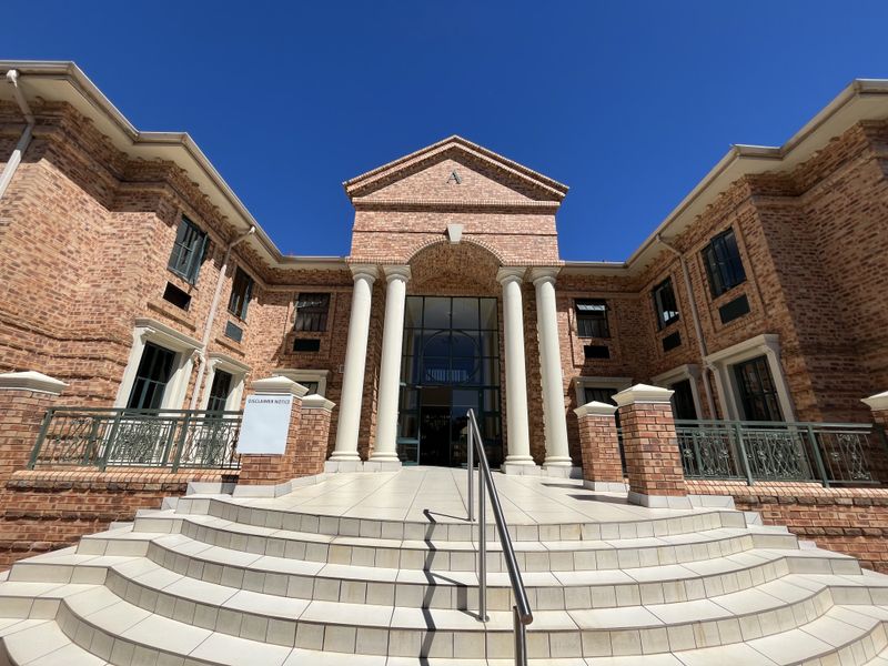 A well-maintained office building entrance featuring a classic brick facade, prominent columns, and a grand tiled staircase leading to the main entry.
