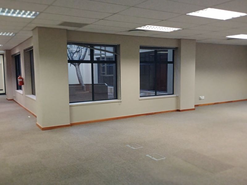 An open-plan office space featuring neutral carpeting, suspended ceilings with recessed lighting, and floor-mounted power outlets, offering a versatile workspace environment.