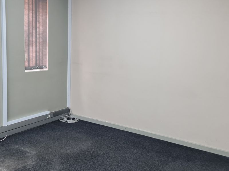 A vacant office space featuring carpeted flooring, vertical blinds, and integrated electrical and data connectivity points.