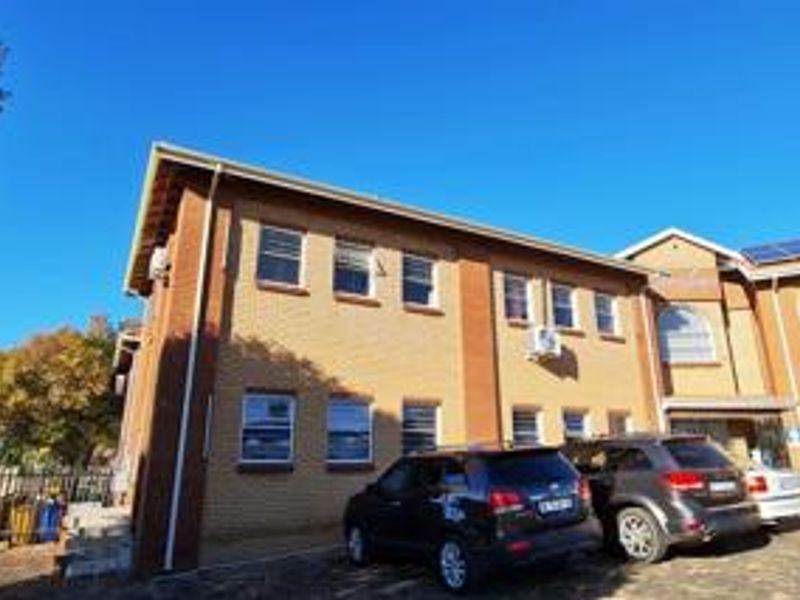 A view of the front exterior of a brick office building featuring a paved driveway and installed air conditioning units.