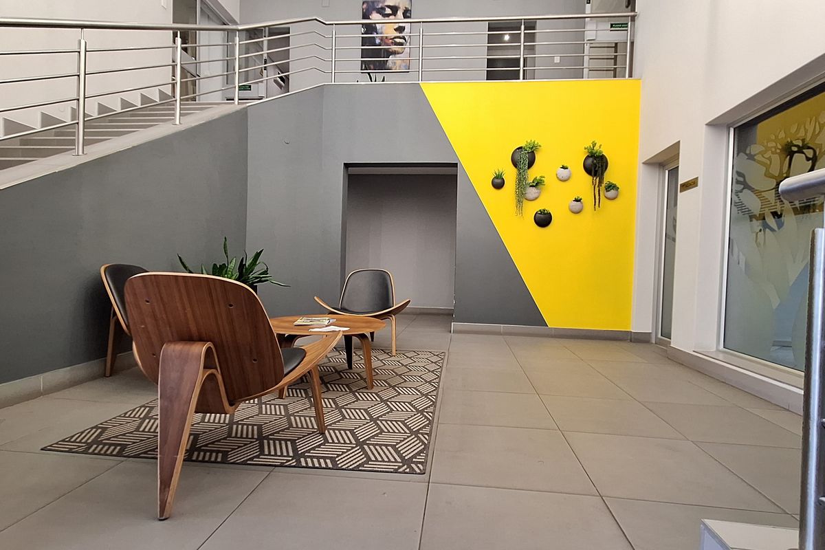 Modern office entrance foyer featuring a staircase with stainless steel balustrades and contemporary tiled flooring.