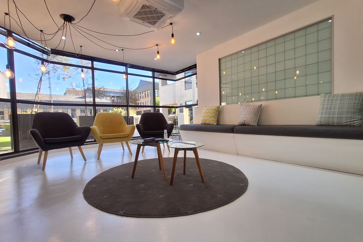 Modern office reception or breakout area featuring floor-to-ceiling windows, built-in bench seating, and a sleek, minimalist design with integrated climate control.