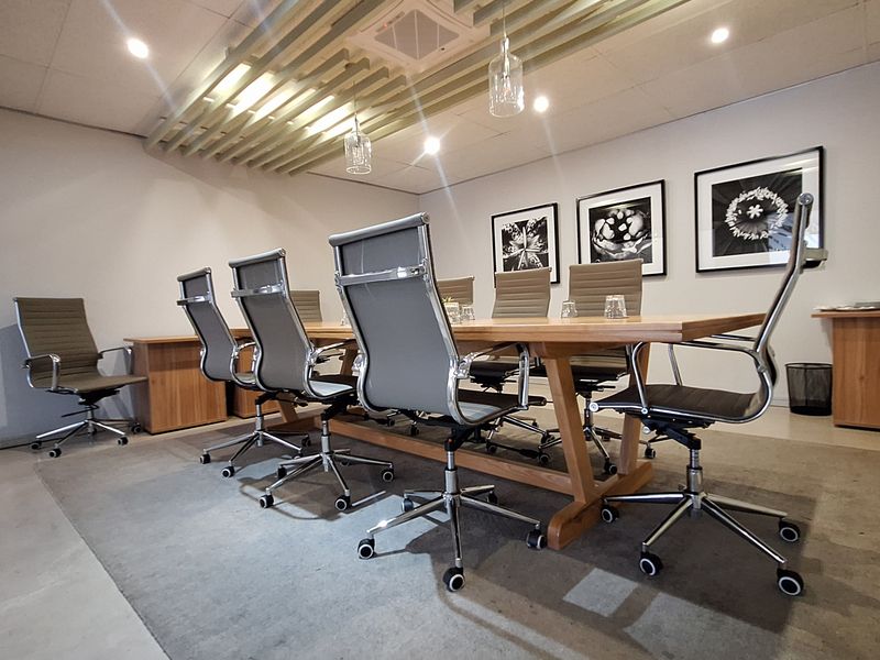 A professional office boardroom featuring a large wooden conference table, modern ergonomic seating, and decorative timber ceiling slats with integrated lighting.