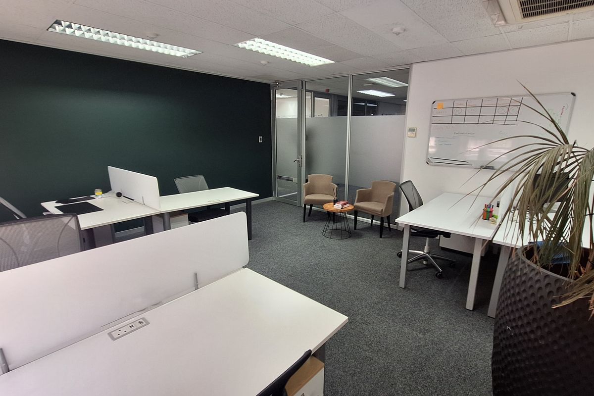A modern, well-maintained office space featuring carpeted flooring, suspended ceilings with recessed lighting, and a glass partition wall for a professional work environment.