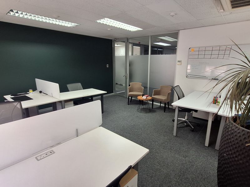 A modern, well-maintained office space featuring carpeted flooring, suspended ceilings with recessed lighting, and a glass partition wall for a professional work environment.