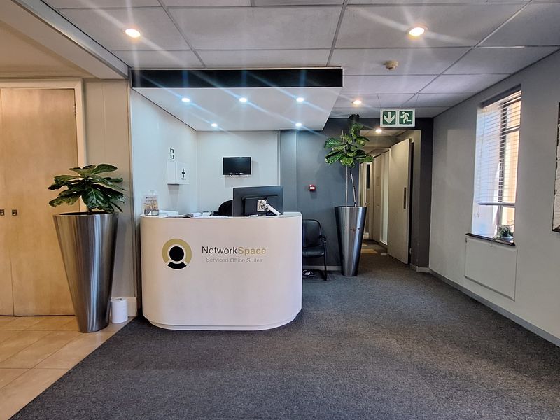 A professional office reception area featuring a modern curved desk, recessed lighting, and neutral finishes, creating a welcoming and functional entry space.