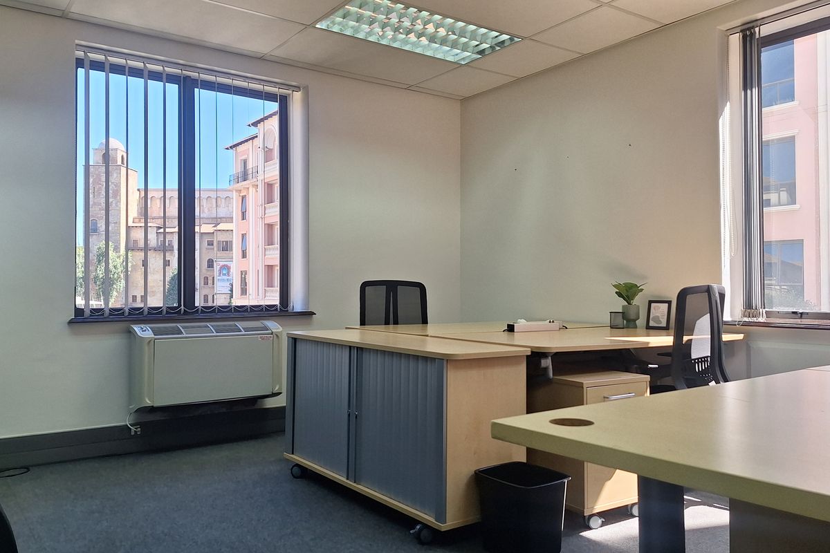 A bright, functional office space featuring large windows with vertical blinds, carpeted flooring, and integrated HVAC climate control.
