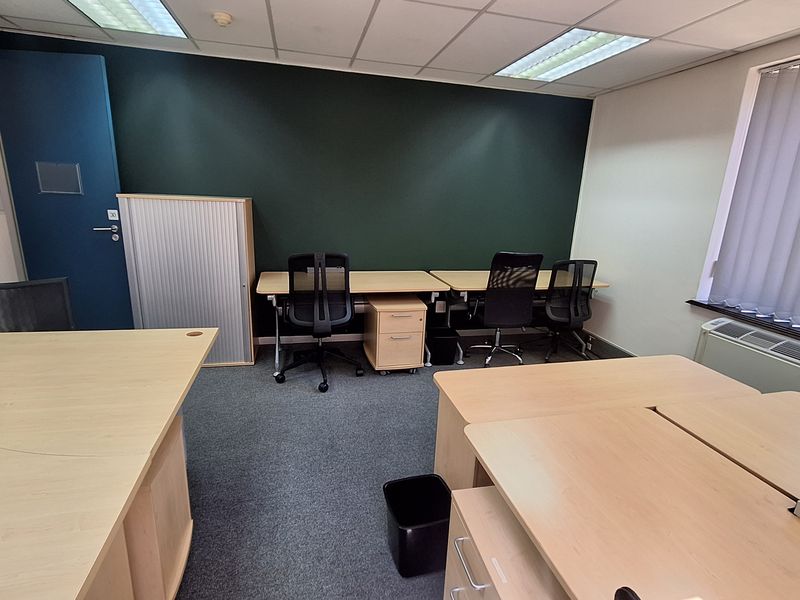 A functional office space featuring carpeted flooring, suspended ceilings with recessed lighting, and an integrated HVAC unit, providing a professional work environment.