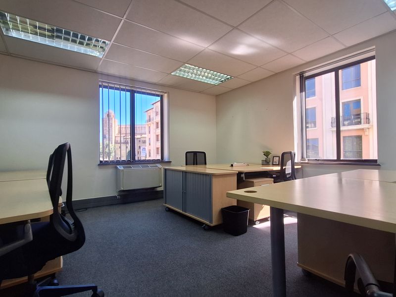 A professional office space featuring carpeted flooring, suspended ceilings with recessed lighting, and an integrated HVAC unit, offering a functional work environment.