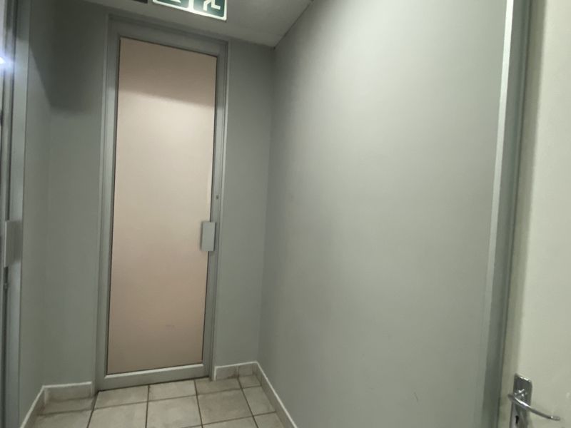 A functional office hallway featuring tiled flooring and an emergency exit door.
