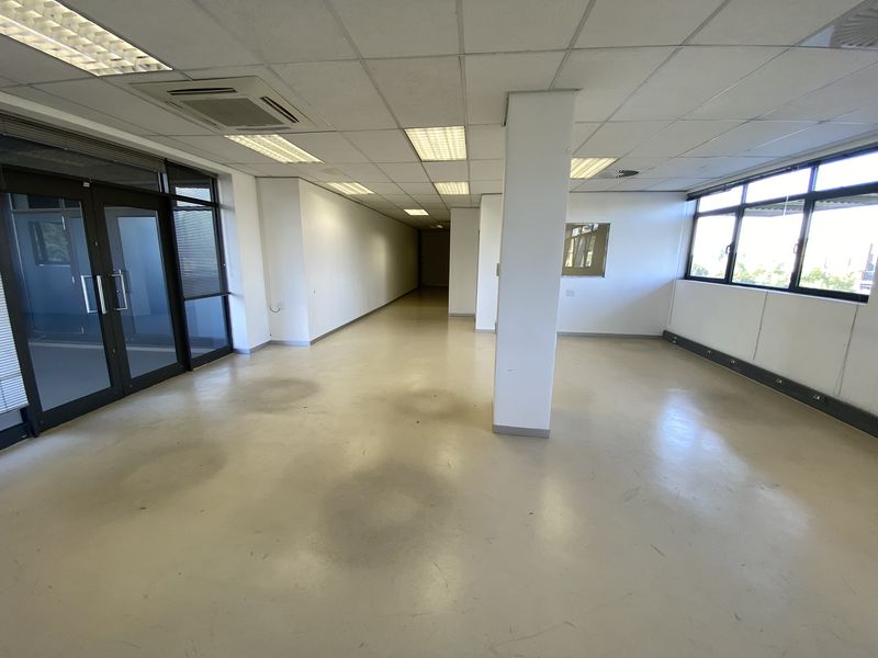 Spacious, open-plan office area featuring suspended ceilings, recessed lighting, central air conditioning, and large windows providing ample natural light.