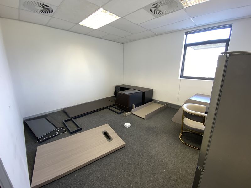 A vacant office space featuring a suspended ceiling, recessed lighting, air conditioning vents, and carpeted flooring.