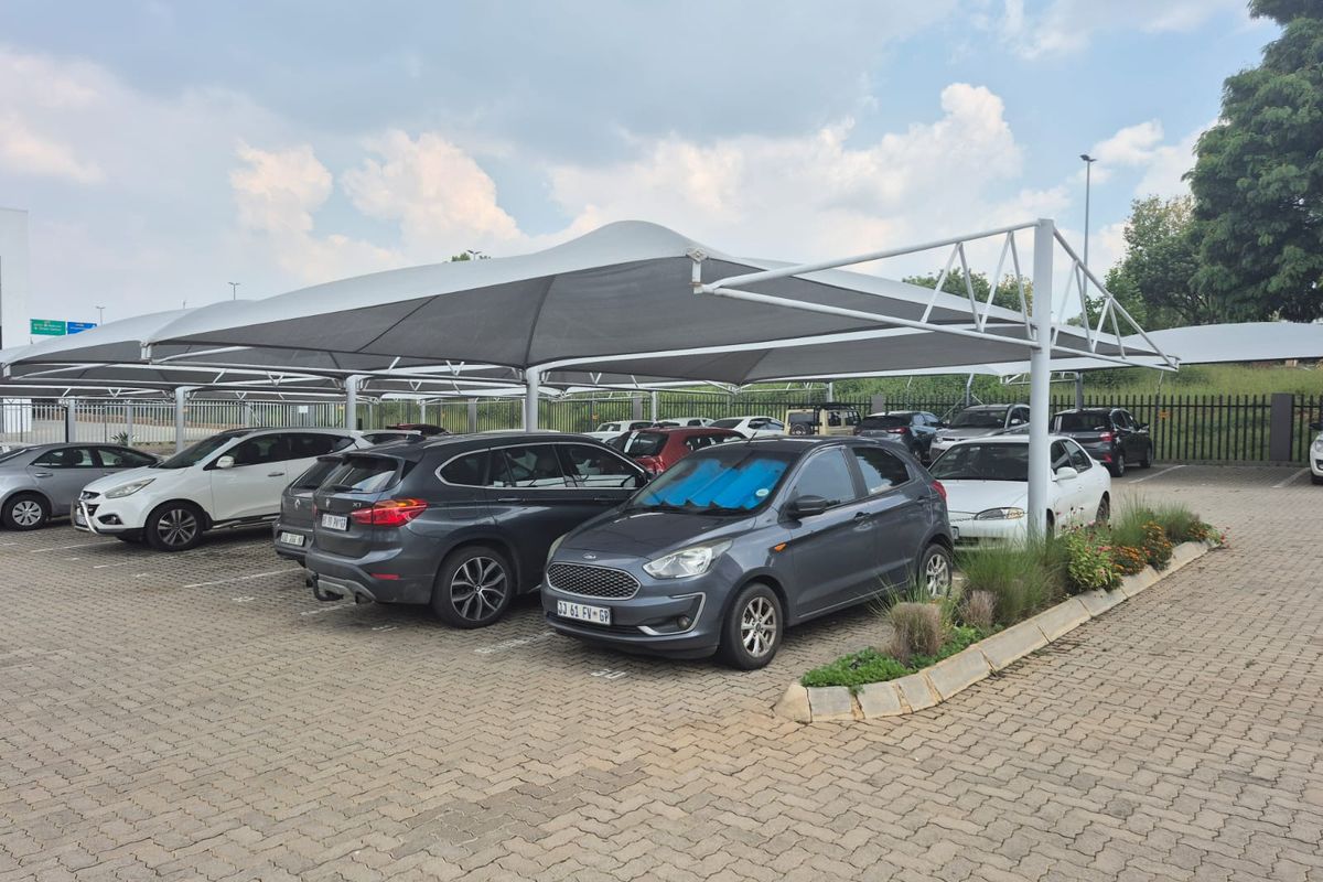 Outdoor parking area featuring paved ground surfaces and structured shade cloth carports for vehicle protection.