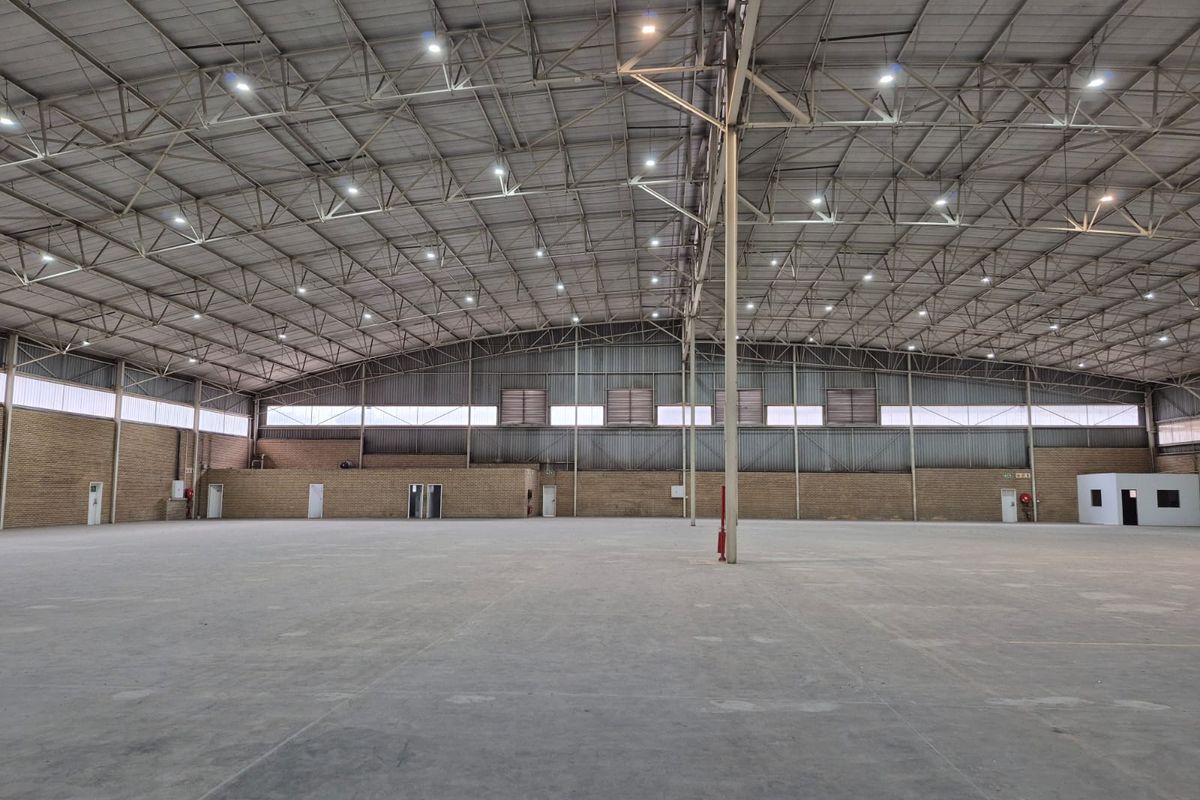 Spacious industrial warehouse featuring a high-clearance steel truss roof, polished concrete flooring, and ample natural light through clerestory windows.