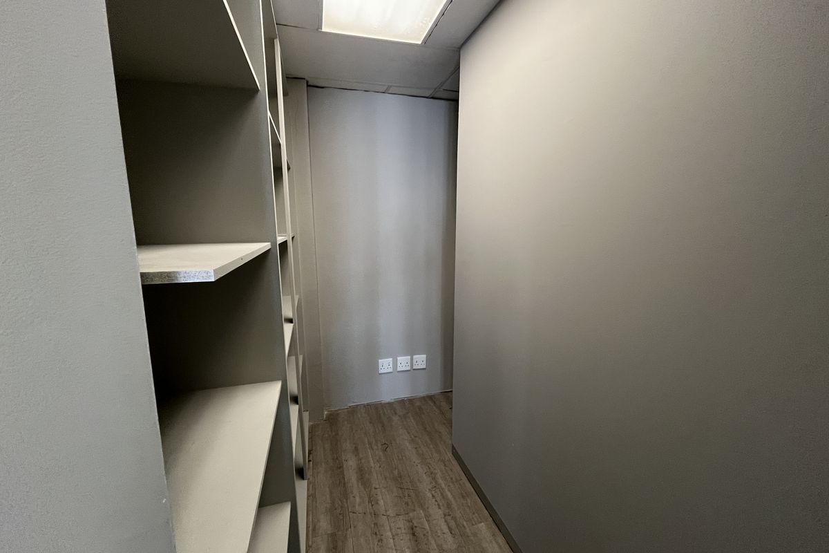 A clean, functional utility or storage space featuring built-in shelving, wood-look flooring, and integrated electrical outlets.
