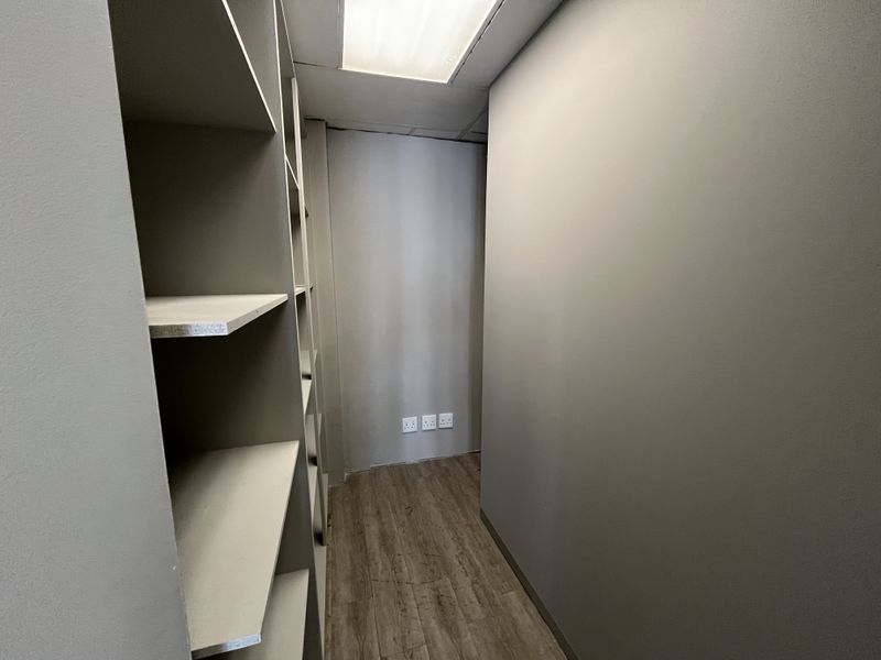 A clean, functional utility or storage space featuring built-in shelving, wood-look flooring, and integrated electrical outlets.