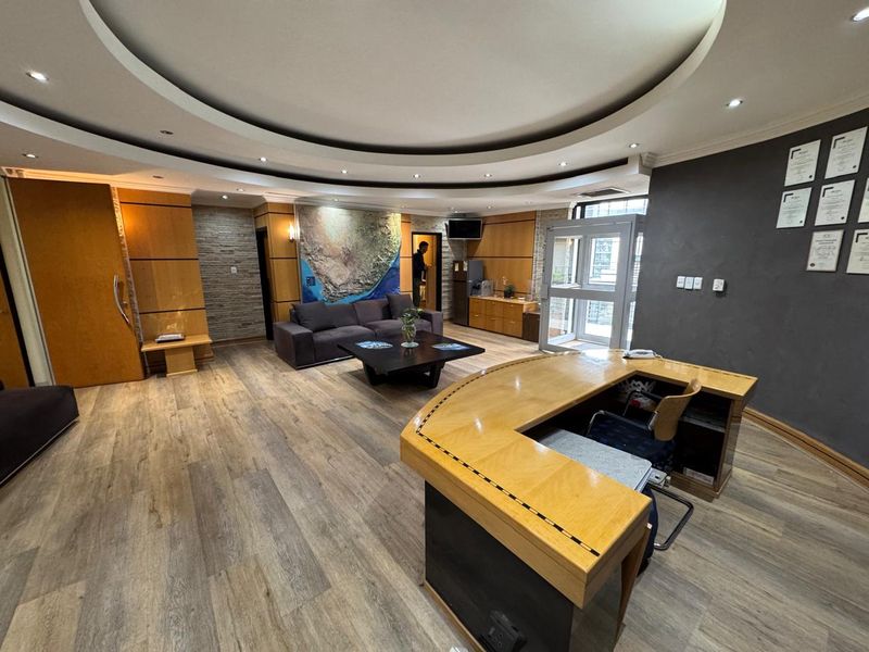 Professional office reception area featuring wood veneer paneling, a stone feature wall, recessed ceiling lighting, and a custom built-in reception desk.