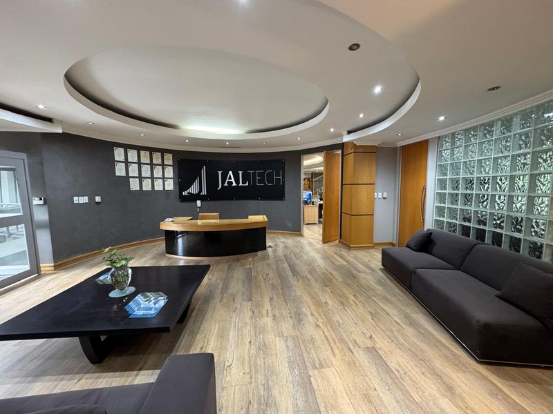Professional office reception area featuring a circular recessed ceiling, wood laminate flooring, and a distinctive glass block feature wall.