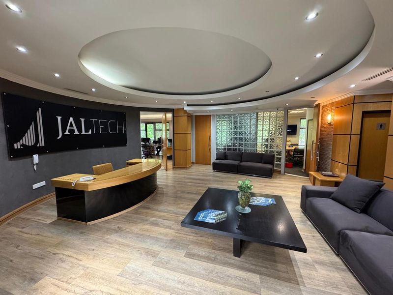 Professional office reception area featuring a circular bulkhead ceiling, wood laminate flooring, and a decorative glass block feature wall.