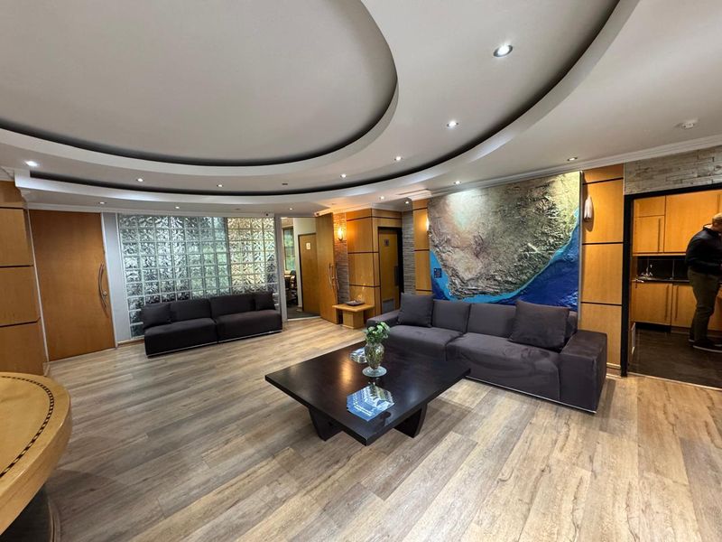 A professional office reception area featuring a unique circular dropped ceiling, glass block accents, and warm wood veneer wall paneling.