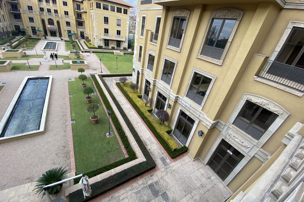 Elevated view of the office complex courtyard featuring landscaped gardens, paved walkways, and a central water feature.