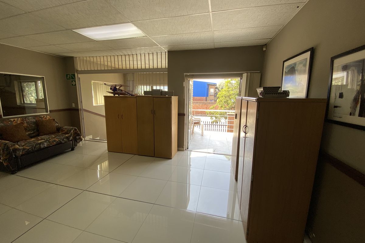 Spacious interior area featuring polished tile flooring, drop ceiling, and direct access to an outdoor balcony through a glass door.