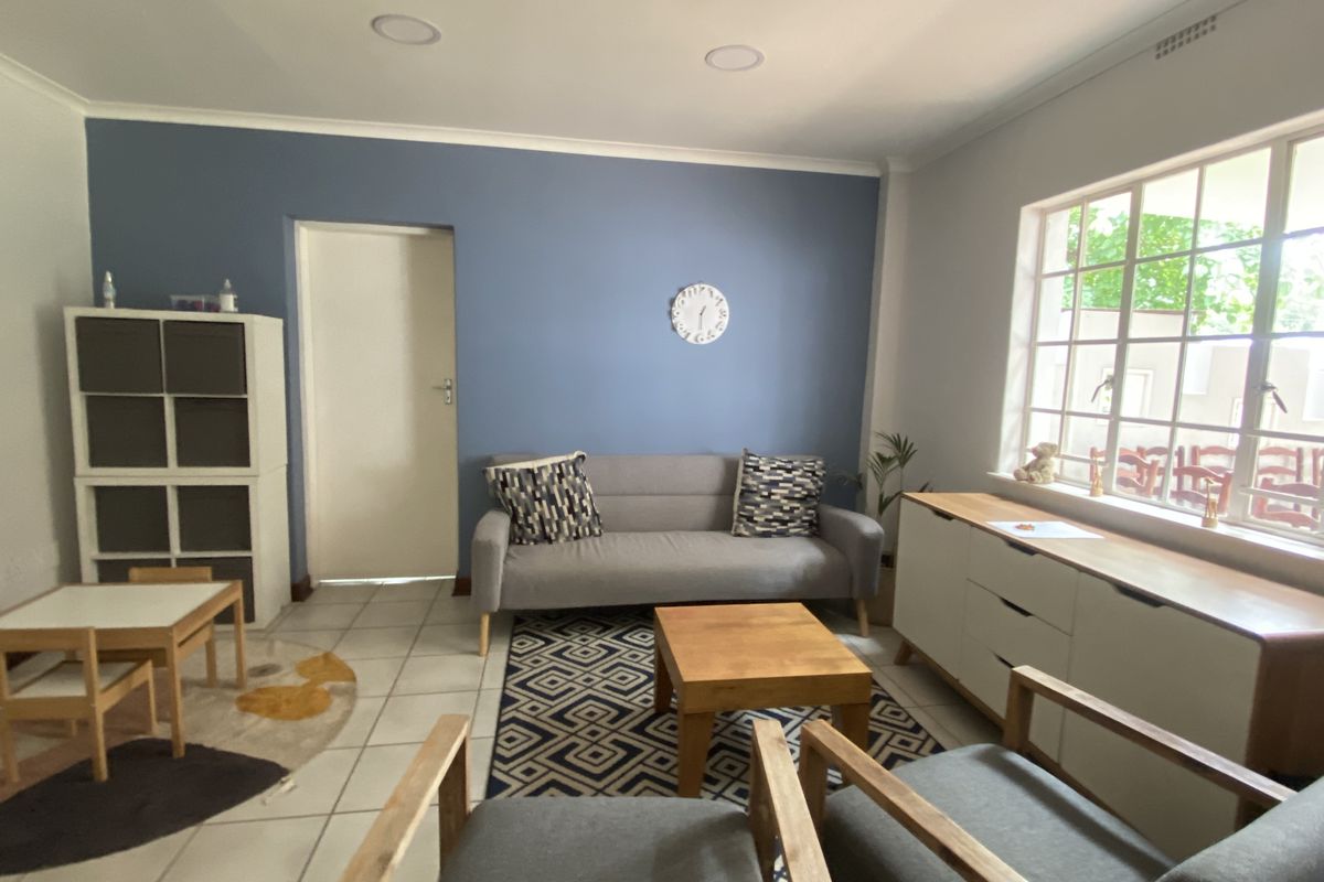 A bright living room featuring tiled flooring, recessed ceiling lighting, and a large window providing natural light.