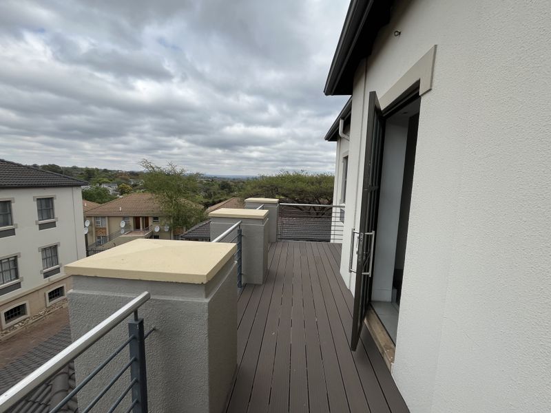 A modern balcony featuring composite decking, stainless steel railings, and a clear view of the surrounding neighborhood.