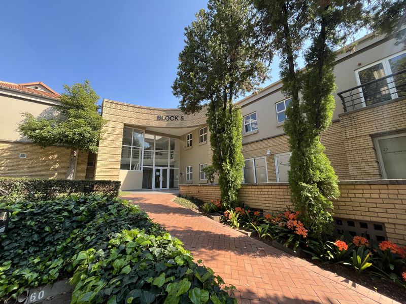 Front exterior view of Block 5 office building featuring a brick facade, paved entrance walkway, and established garden landscaping.