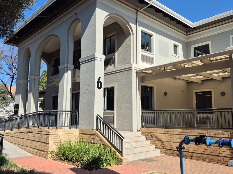 Front exterior view of a professional office building featuring an arched portico, brick retaining walls, and accessible paved walkways.