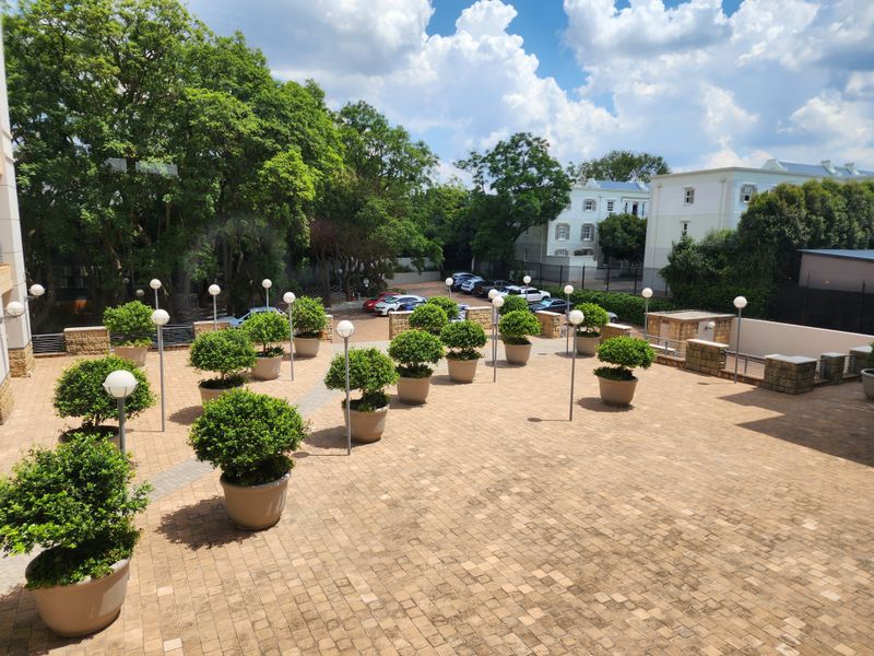 A spacious paved outdoor terrace featuring stone retaining walls and integrated lighting, providing a well-maintained communal area for the office property.