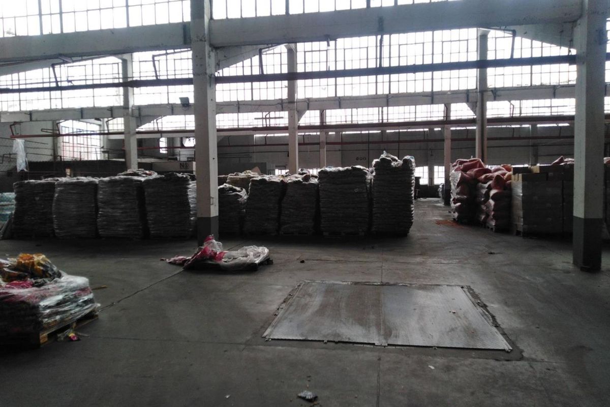 Spacious industrial warehouse area featuring high ceilings, extensive natural light through large clerestory windows, and durable concrete flooring suitable for storage or manufacturing.