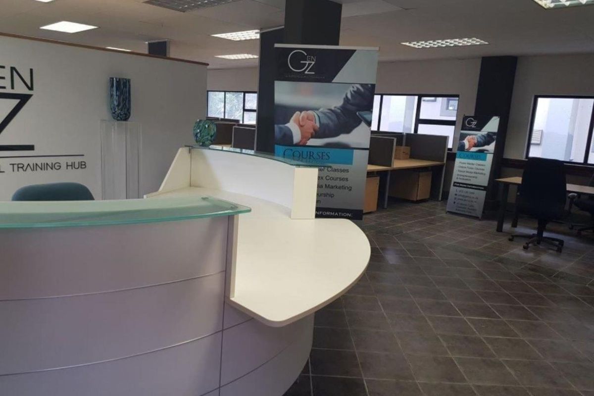A professional office space featuring a modern reception desk, tiled flooring, partitioned workstations, and recessed lighting in a suspended ceiling.