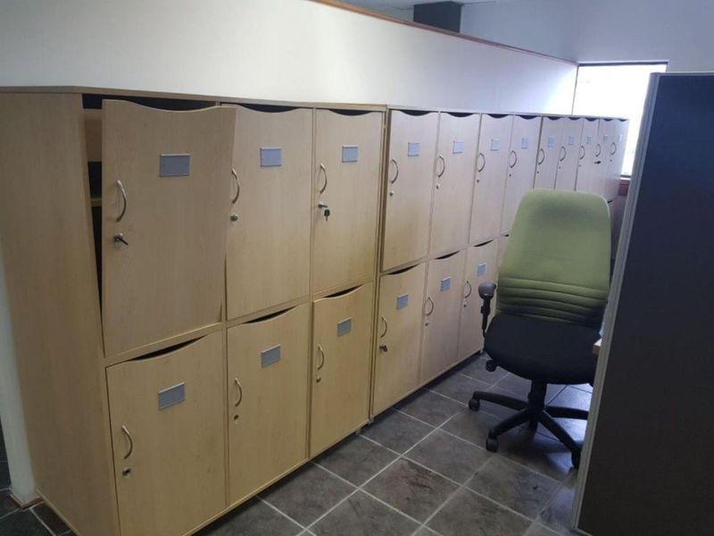 Office space featuring a wall of built-in storage lockers and tiled flooring, providing functional storage solutions for a professional work environment.