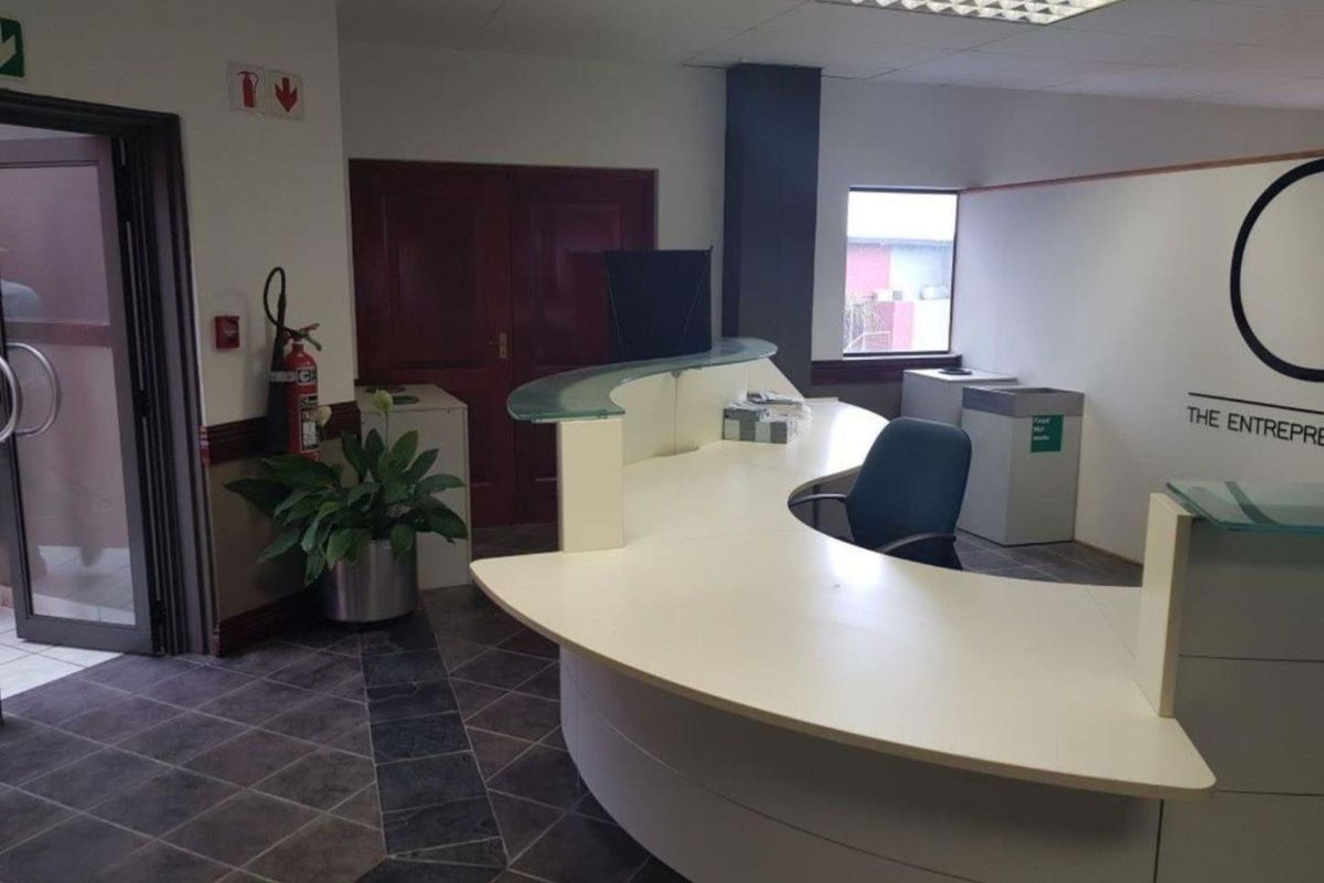 Professional office reception area featuring a curved built-in desk, tiled flooring, and a drop ceiling, providing a functional welcome space for clients.