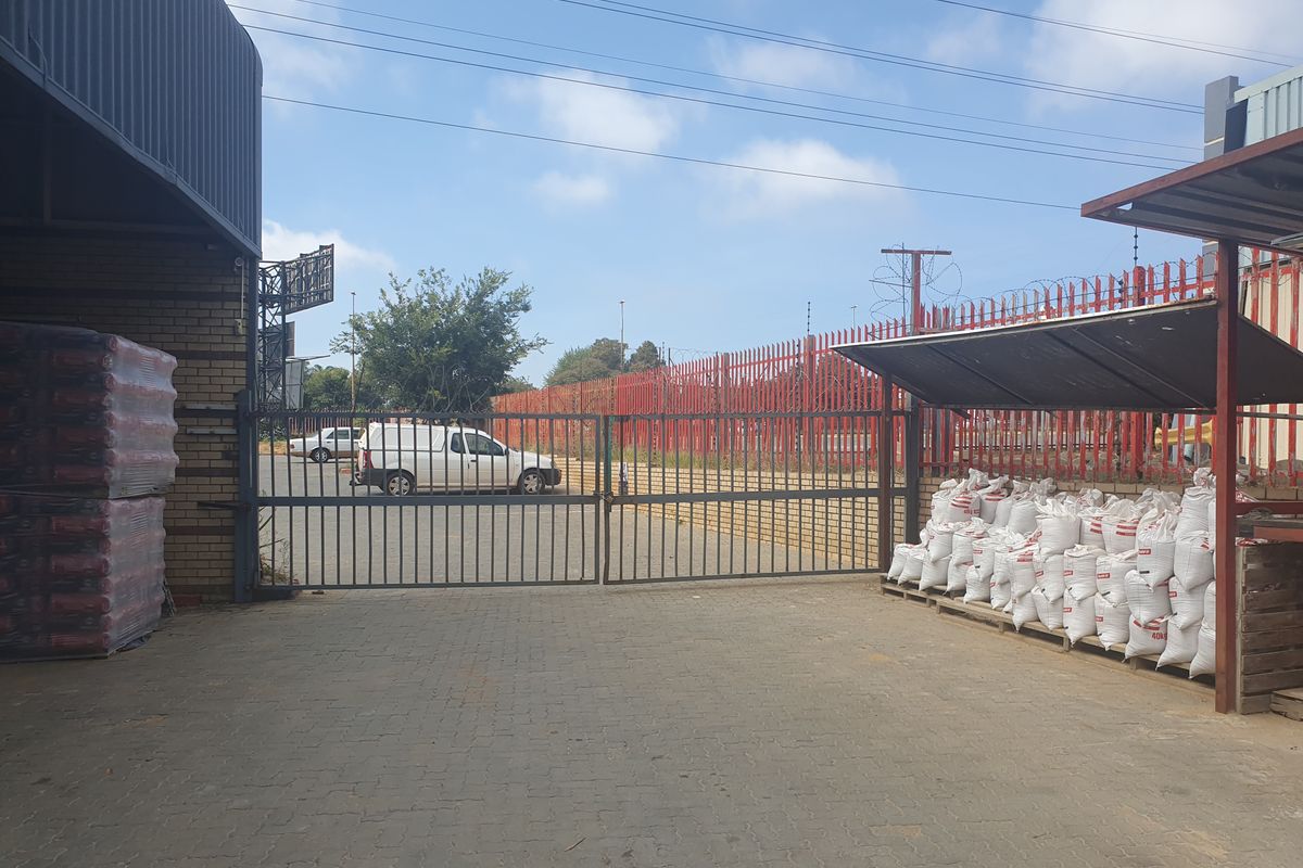 Industrial yard area featuring paved ground, secure perimeter fencing, and covered loading or storage bays.
