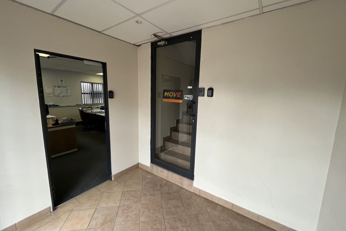 A functional office entry area featuring tiled flooring, a suspended ceiling, and secure glass door access with integrated keypad entry systems.